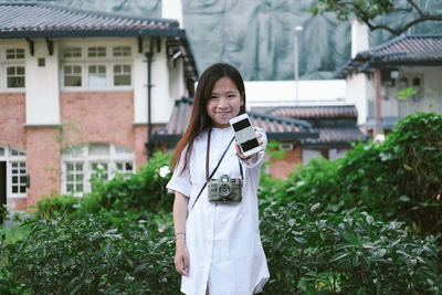 Smiling young woman standing against plants