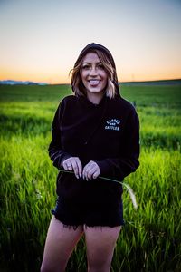 Portrait of smiling young woman standing on field