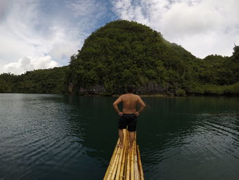 Rear view of shirtless man in lake against sky