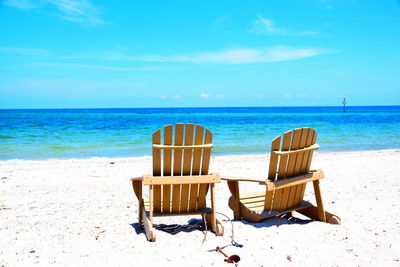 Chairs on beach against blue sky