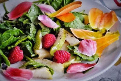 Fruit and vegetable leaf salad with pink and yellow flower petals