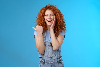 Portrait of smiling young woman against blue background