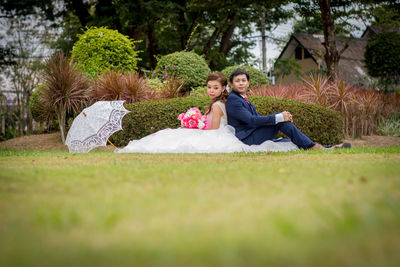 Newlywed couple romancing on grassy field at public park