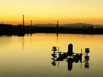 Silhouette boat in lake against sky during sunset