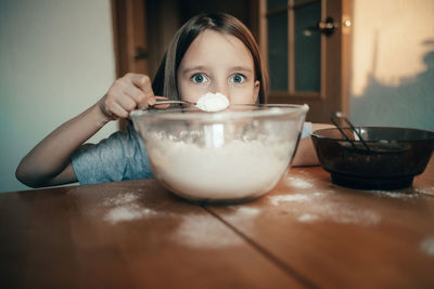 Portrait of cute girl holding flour in spoon