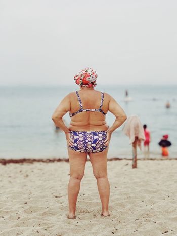 REAR VIEW OF PERSON STANDING ON BEACH