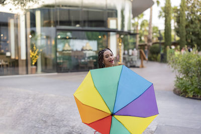 Woman holding colorful umbrella on footpath