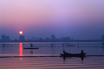 Silhouette boats in sea against sky at sunset