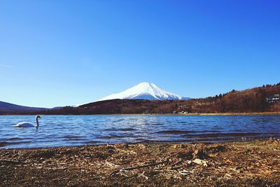 Scenic view of lake and mountains against clear blue sky