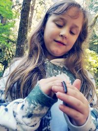 Close-up of girl holding tree trunk