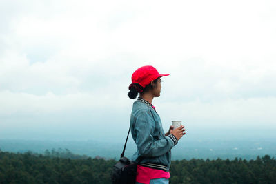 Side view of man holding umbrella against sky