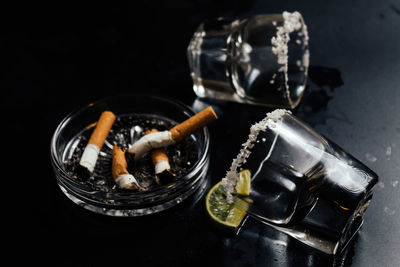 High angle view of shot glasses by cigarette butts on table