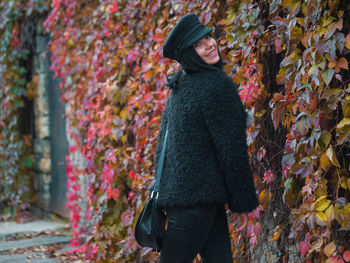 Portrait of smiling young woman standing in park during autumn