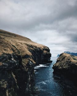 Scenic view of cliff by sea against sky