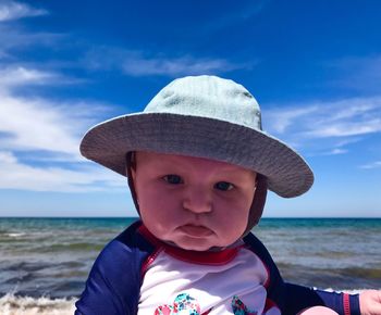 Close-up portrait of cute boy at beach against sky