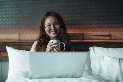 Portrait of young woman using laptop on table at home