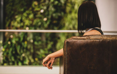 Rear view of woman sitting on sofa at home