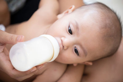 Midsection of person feeding milk to baby girl at home