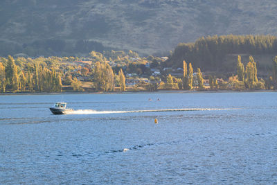 Sceneic view of lake with speed boat with mountains in the background