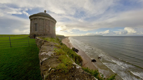 Lighthouse by sea against sky