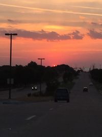 Cars on road against sky during sunset