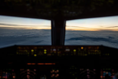 Airplane window against sky during sunset