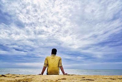 Rear view of man looking at sea against sky