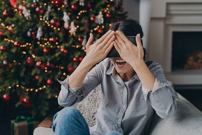 Young woman sitting on christmas tree at home