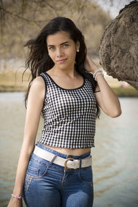 Portrait of young woman standing against waterfall