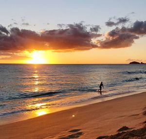 Silhouette man on beach against sky during sunset