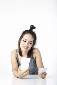 Young woman using smart phone against white background