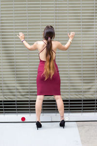 Full length rear view of woman standing against wall