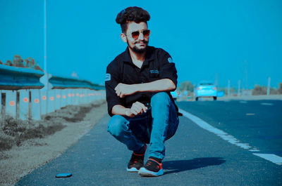 Portrait of young man sitting in car against sky