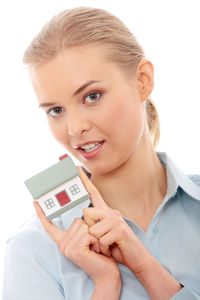 Portrait of smiling young woman holding camera over white background