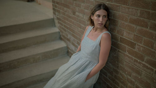 Portrait of a beautiful young woman on staircase against wall