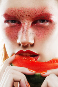 Close-up portrait of serious young woman biting watermelon slice