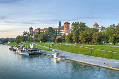 Scenic view of river by buildings against sky