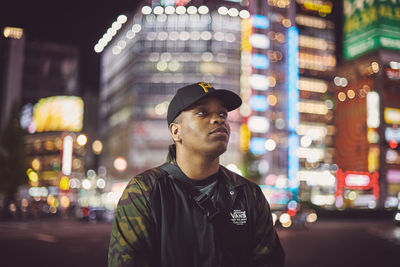 Portrait of young man looking away in city at night