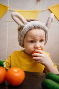 Baby in rabbit ears eats vegetables carrot cucumber easter