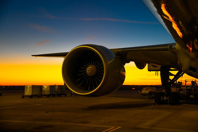 Airplane on airport runway against sky during sunset