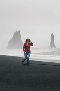 Smiling woman running along black beach scenic photography