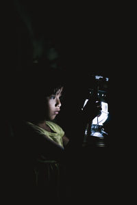 Portrait of boy photographing in darkroom