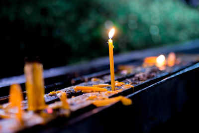 Close-up of lit candles on railing in temple