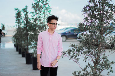 Young man standing in city against sky