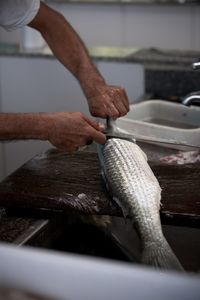 Midsection of man holding fish at kitchen