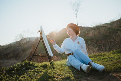 Rear view of woman sitting on land against sky