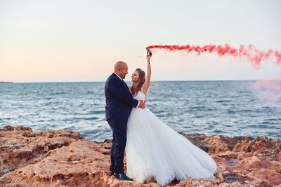 Rear view of couple at beach against sky