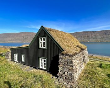 House on field against clear blue sky