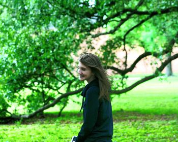 Happy woman against tree at park