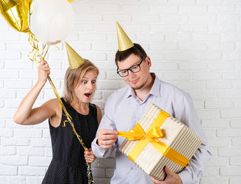 Happy young man holding balloons against white background